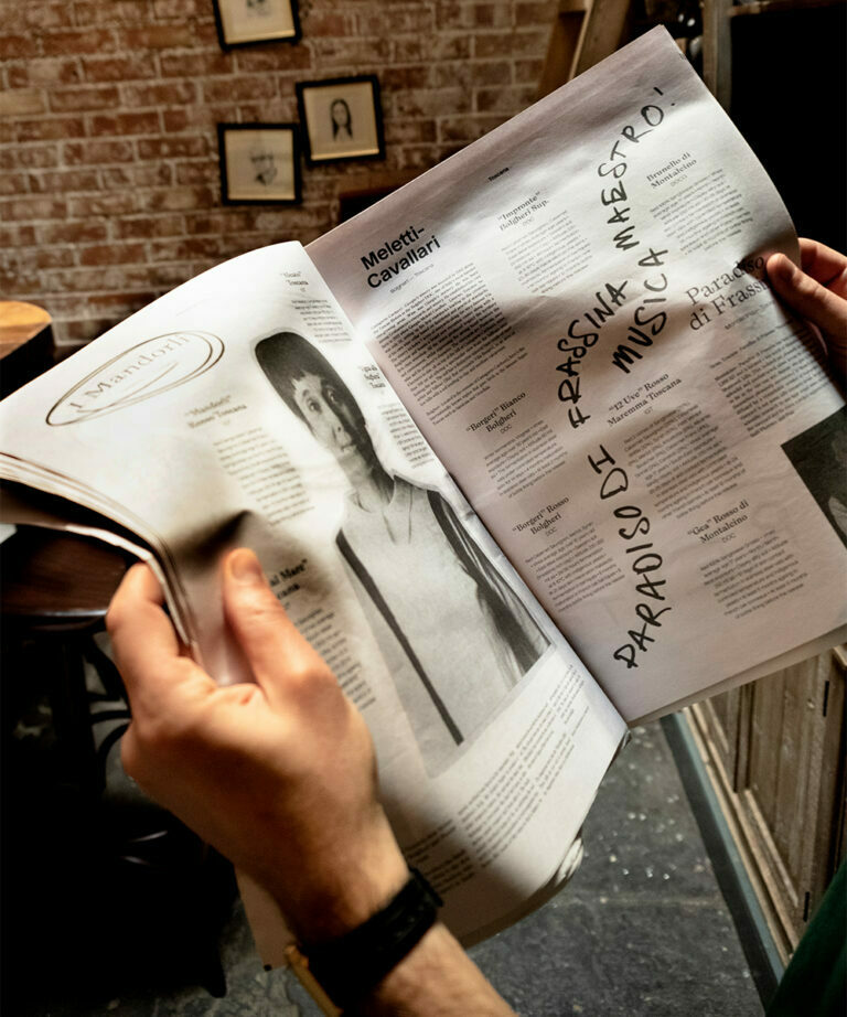 A pair of hands holding an open copy of the Passione Vino newspaper